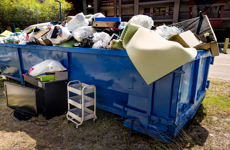 Blue dumpster loaded with garbage and junk